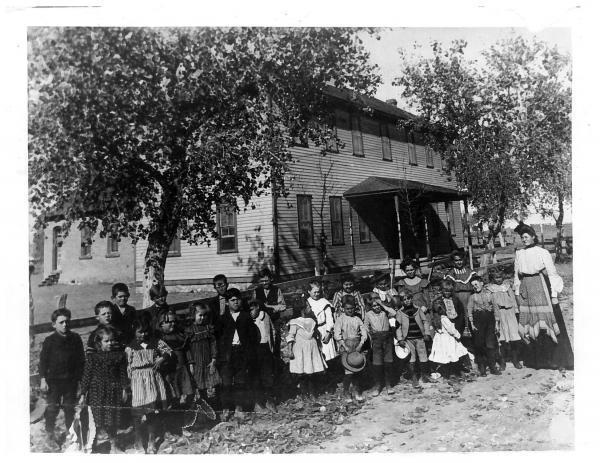 black and white photo of Hagerman student body and Hannah Blackstone standing in front of old school building circa early 1900s